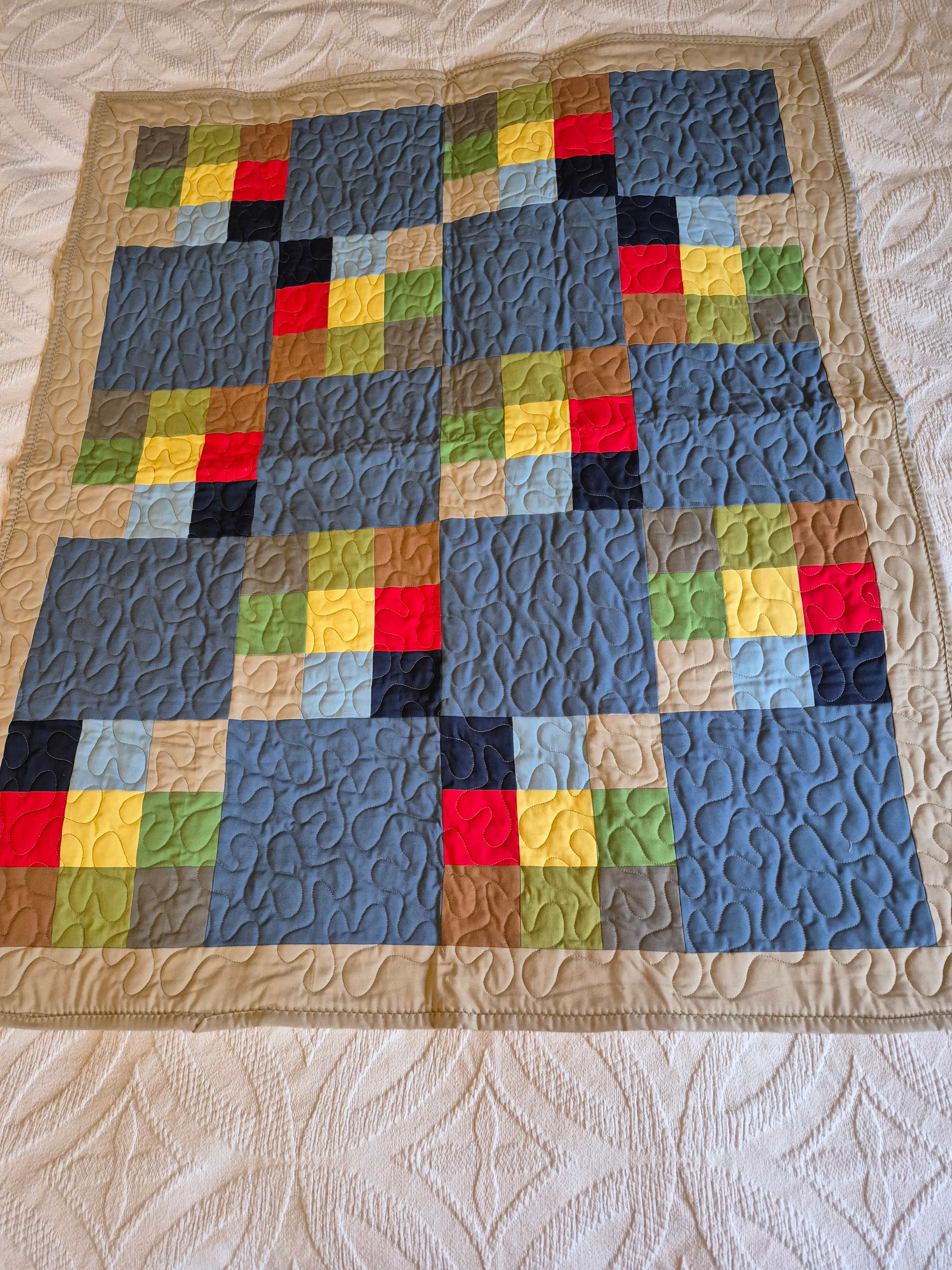 Colorful patchwork quilt with earth tone blocks on tan background