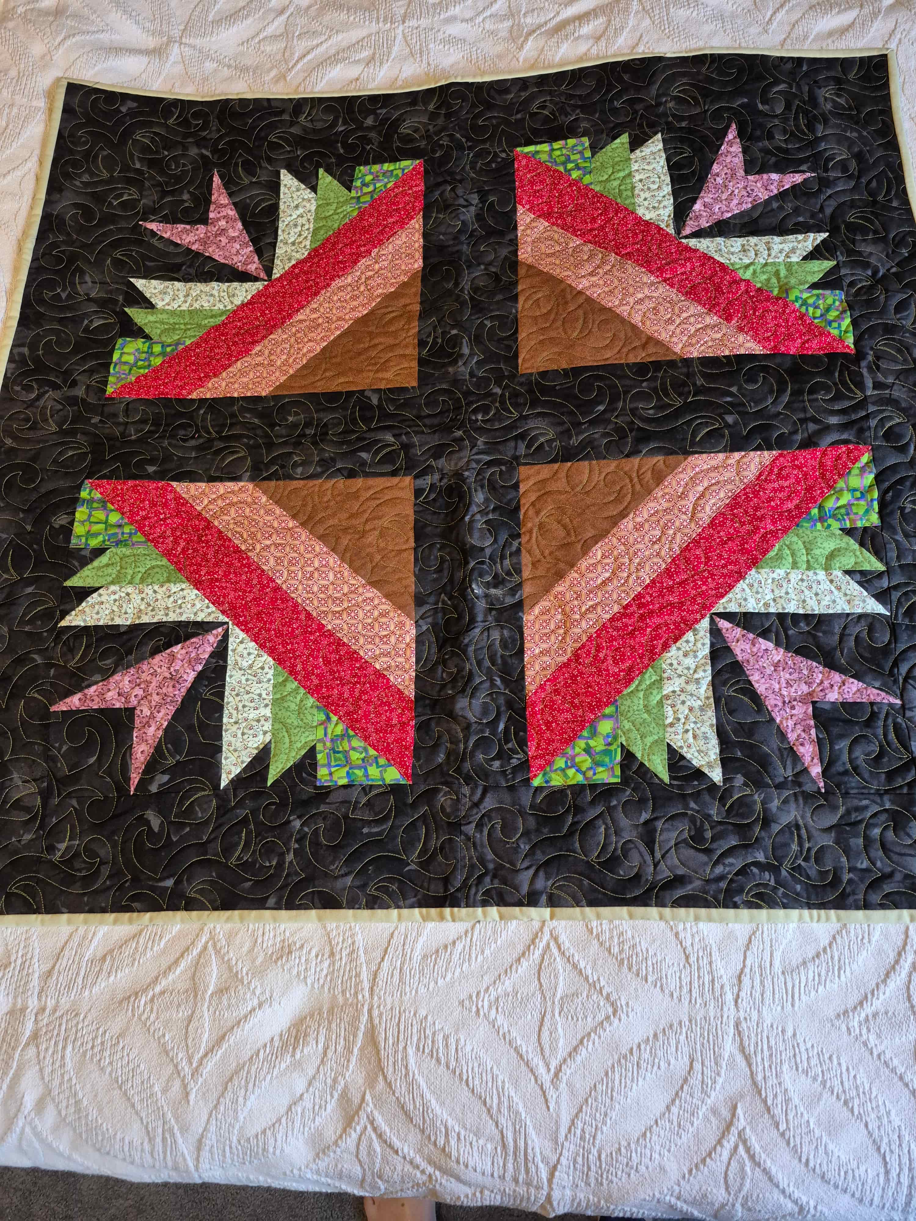 Dramatic leaf pattern quilt with black background and colorful geometric center