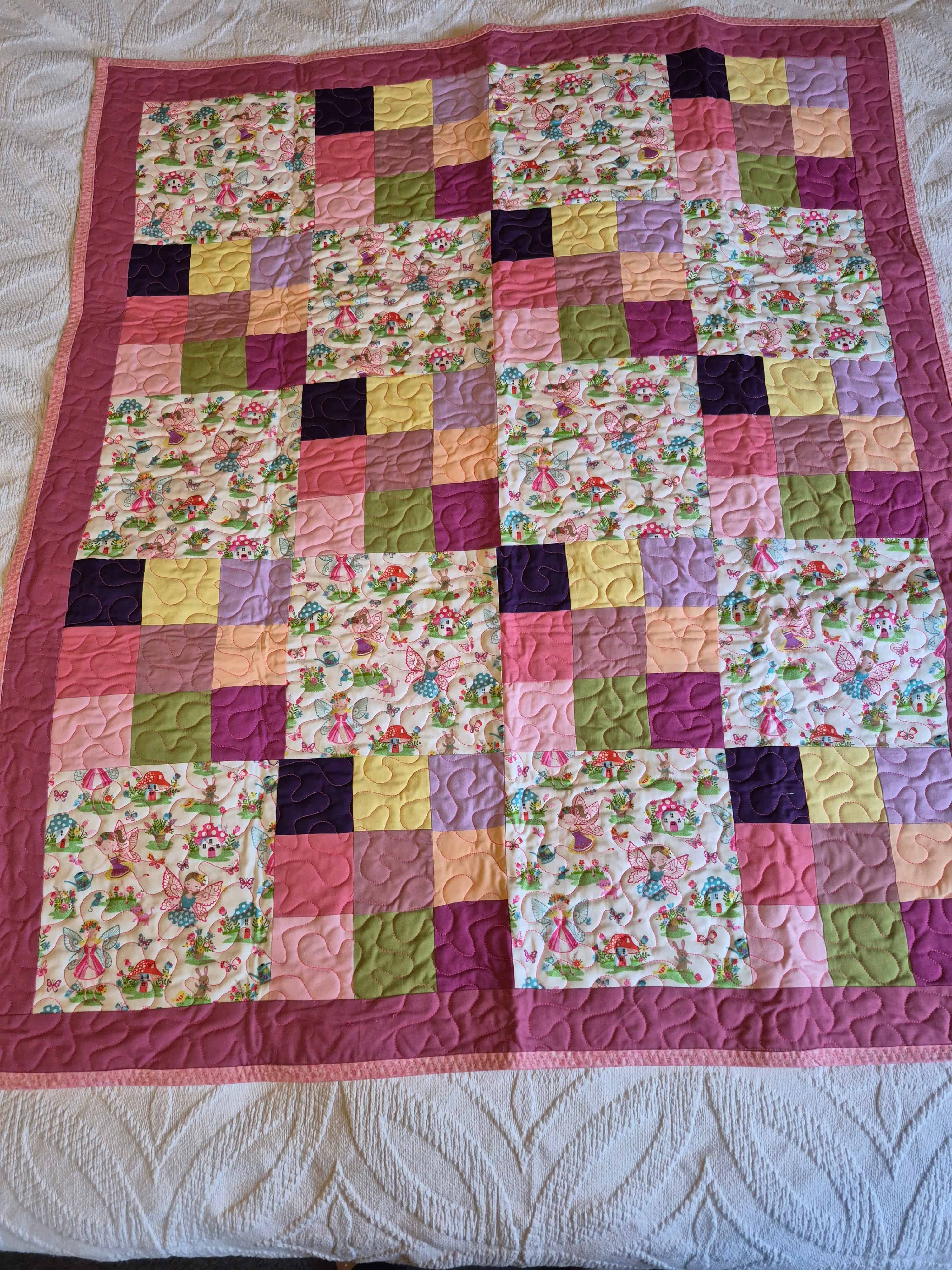 Whimsical fairy-themed baby quilt with pink patchwork blocks