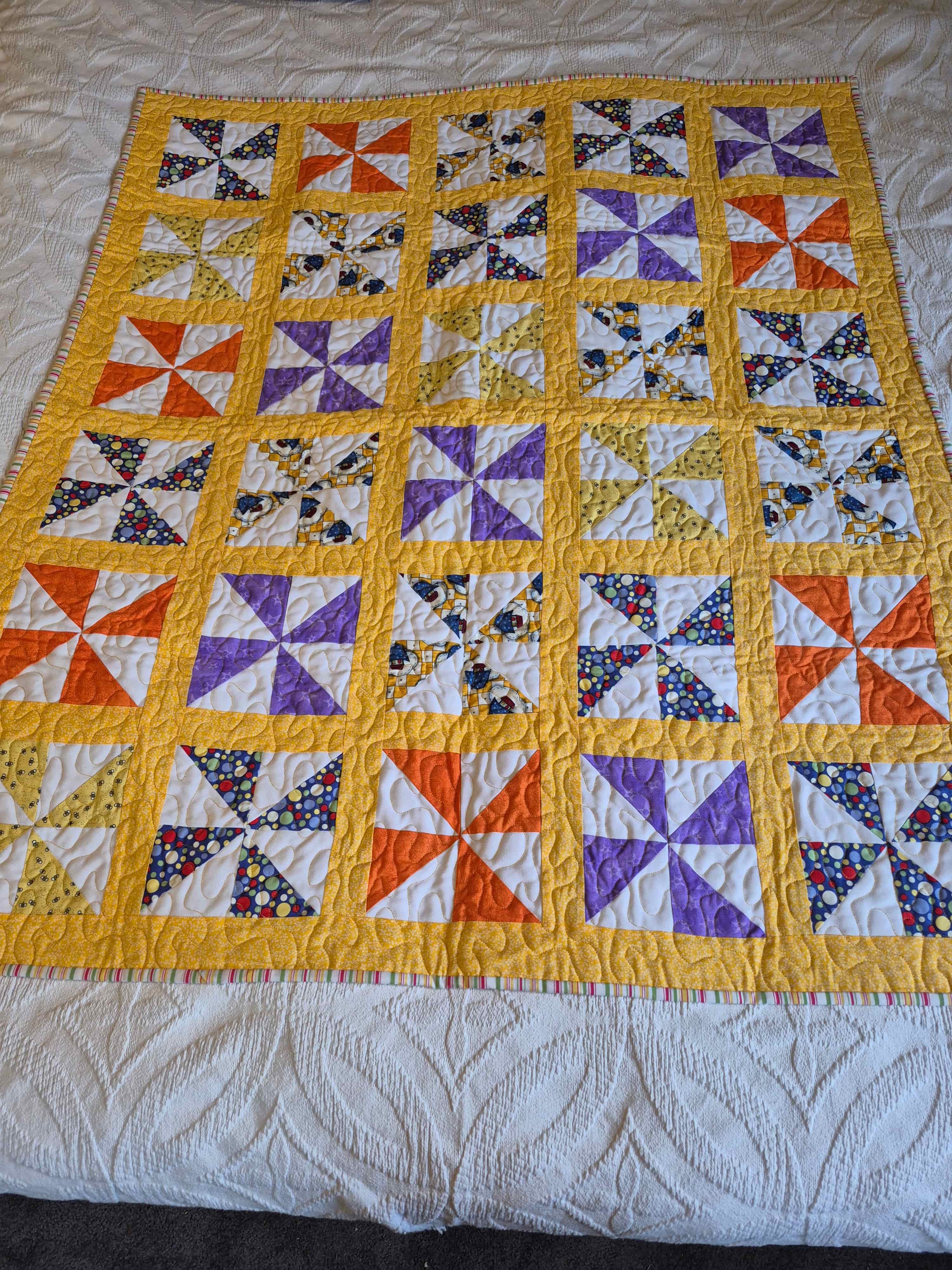 Bright pinwheel quilt with golden yellow sashing and colorful blocks