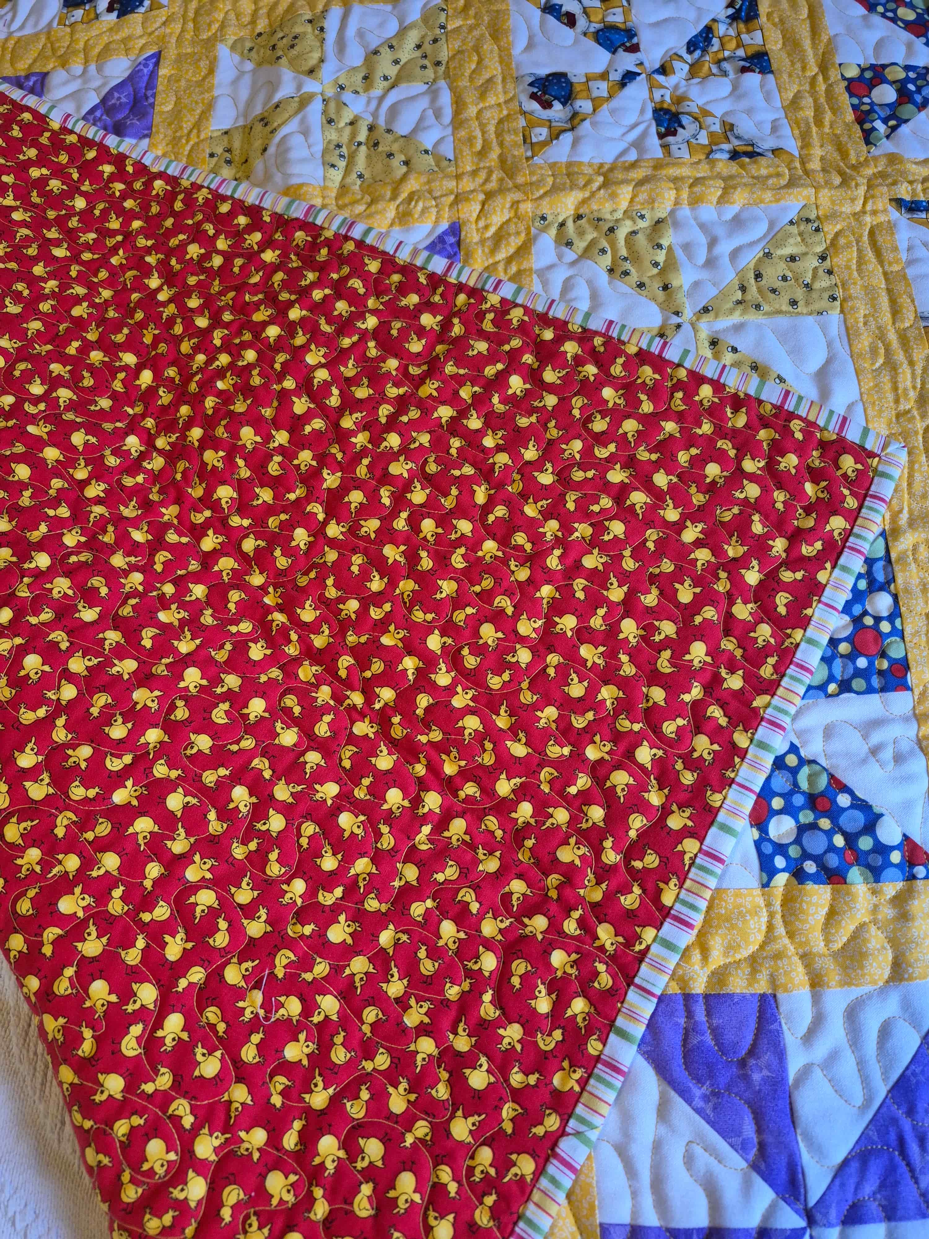 Sunshine pinwheel quilt folded to show red backing with yellow chick print