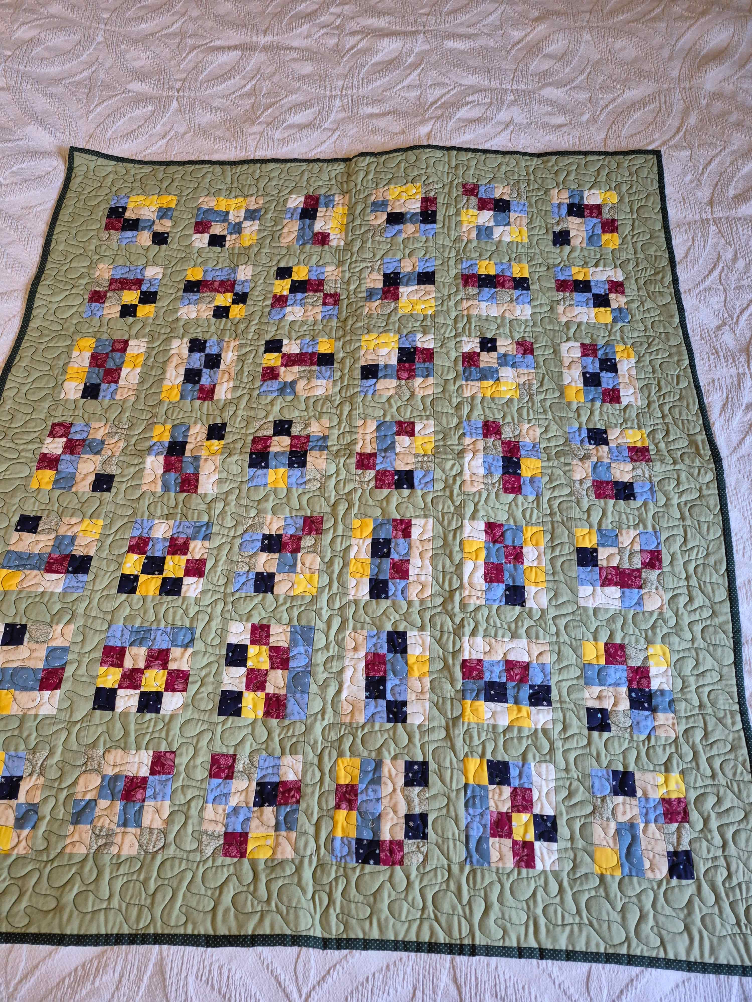 Sage green patchwork quilt with colorful nine-patch blocks